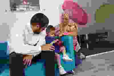 Child on sofa with parents in a smart money cymru branch